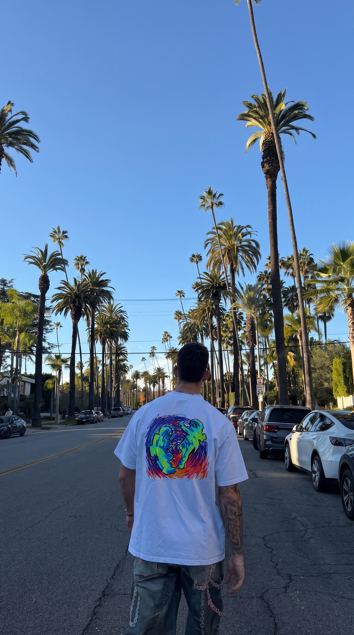 Pluto x Baby Pluto tee, back print worn on a palm-lined street