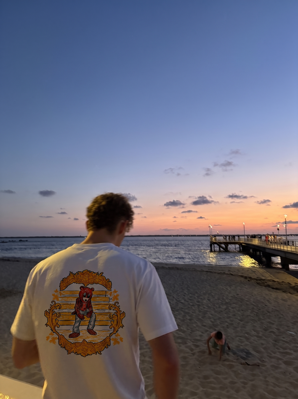 The College Dropout tee, back print worn on the beach at sunset
