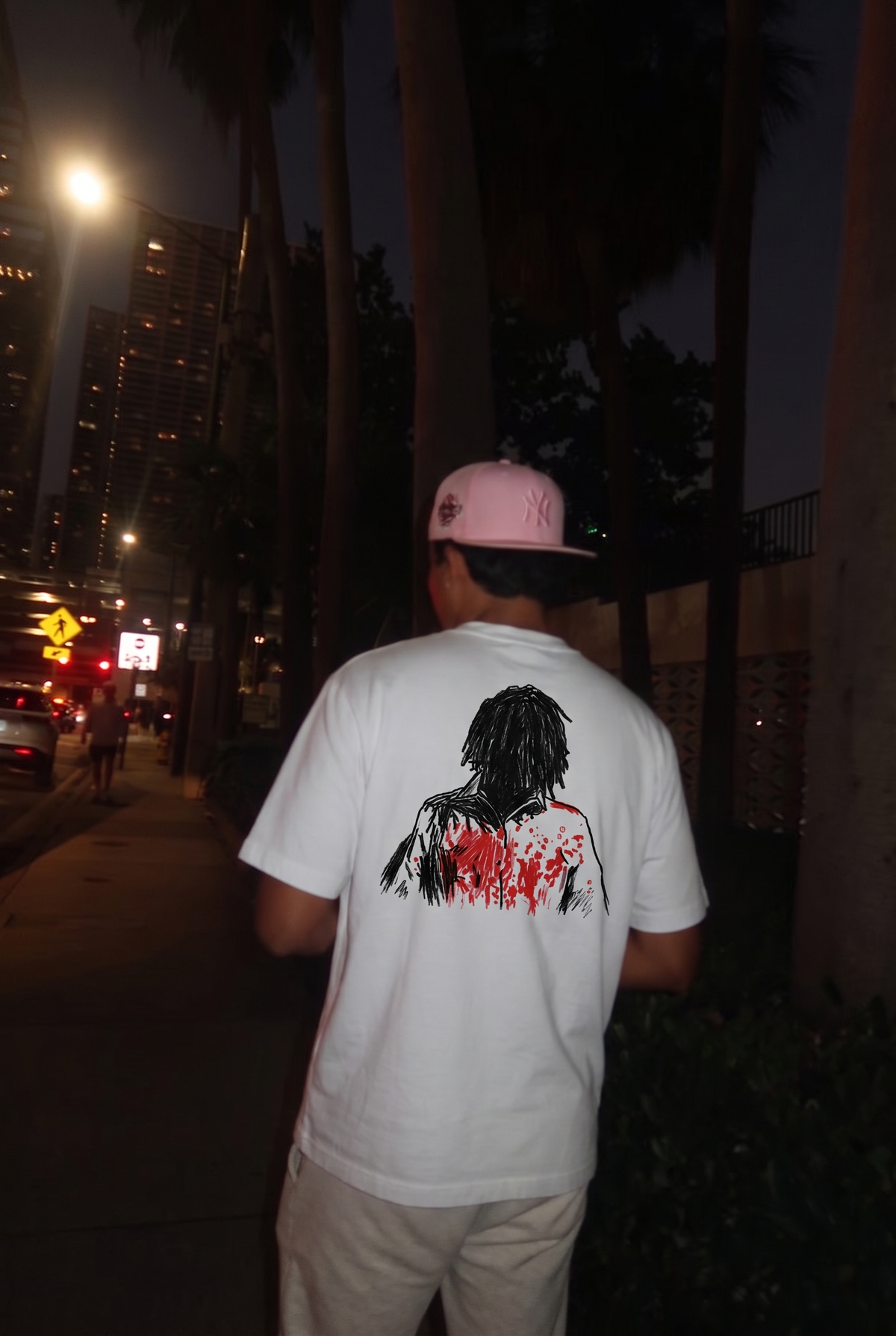 More Chaos tee, back print worn on a city street at night